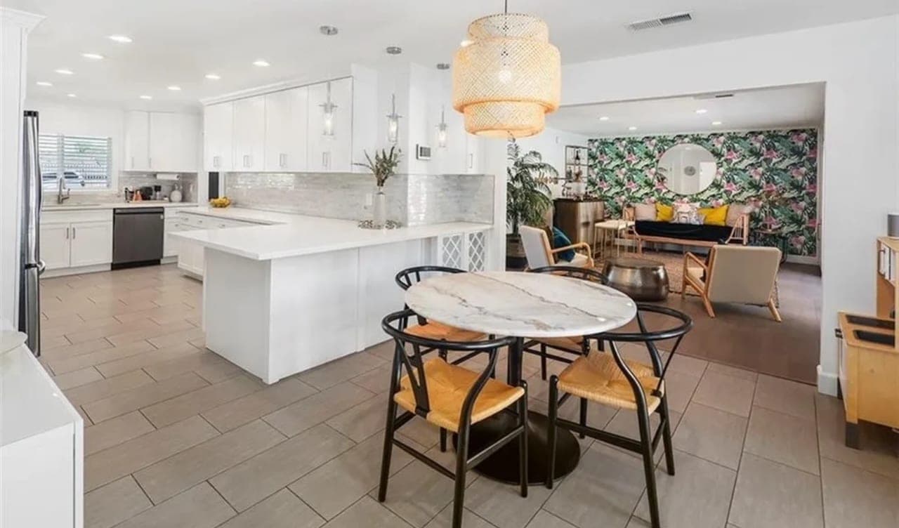 An open kitchen with an island and stools, and a round dining table beyond it.
