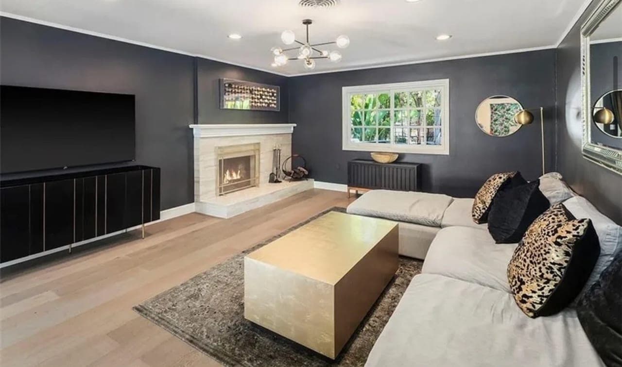A living room with a sectional sofa, a fireplace and a wall-mounted television.