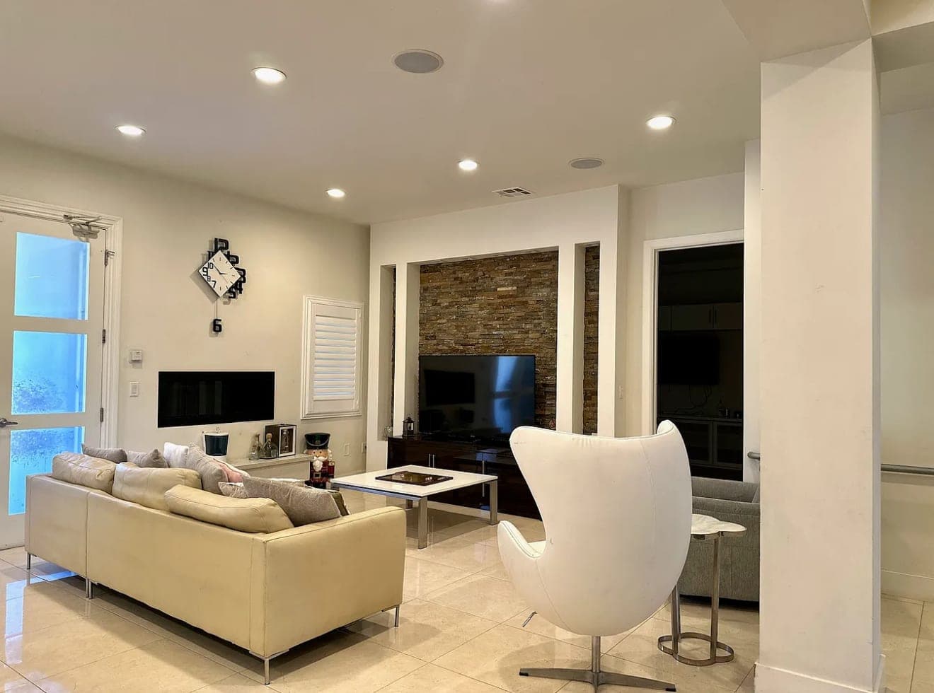 A lounge with a low sofa, a stone-clad fireplace and a white armchair.