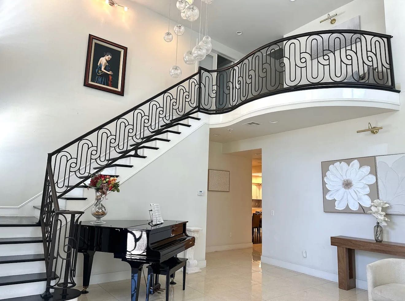 A curved staircase with a wrought-iron rail, with a piano standing beside it.